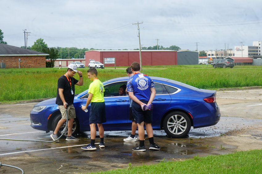 Volunteers from Neshoba Central High School JROTC pray with a car-wash customer during the prayer driver through event.